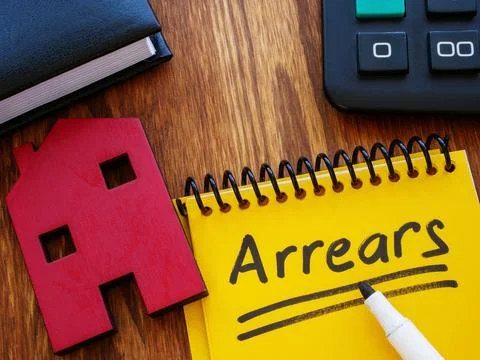 Notepad with word arrears and model of house. Stock Photos