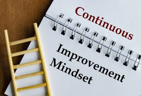 Notepad with the words Continuous Improvement written across lined pages. Stock Photos