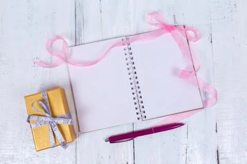 A notepad for your text and a gift. Top view on a wooden table Stock Photos