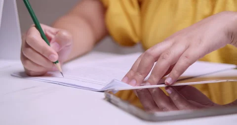 Notes in diary. Pan shot of An asian woman in yellow clothes scribbling Stock Footage 269750961