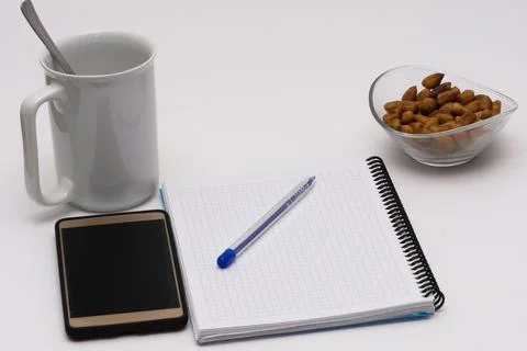 Notes, pen, smart phone, empty cup and the glass bowl filled with hazelnuts Stock Photos