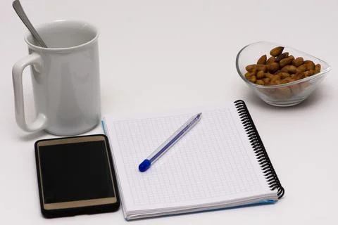Notes, pen, smart phone, empty cup and the glass bowl filled with hazelnuts Stock Photos