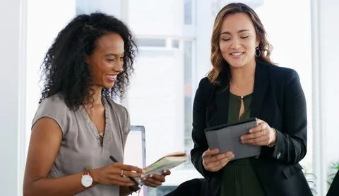 Nothing completes a work task like teamwork. two young businesswomen using a Fotos de archivo