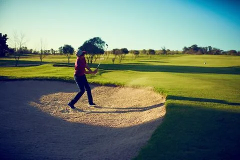 Nothing stands between him and the ball, not even sand. a young man hitting the Stock Photos