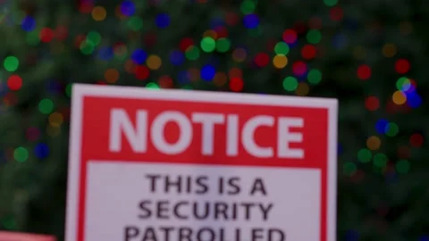 Notice this is a security patrolled sign in front of a Christmas tree Stock Footage 146504663