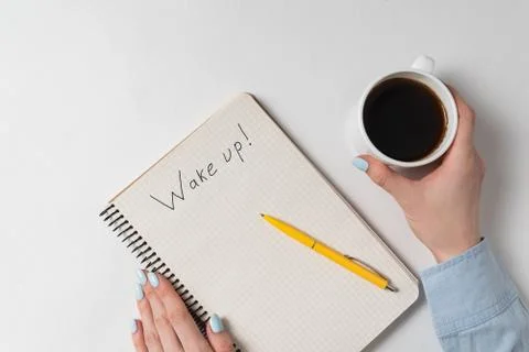 Notice Weke Up in Notepad on white background. Top view of female hands, note Stock Photos