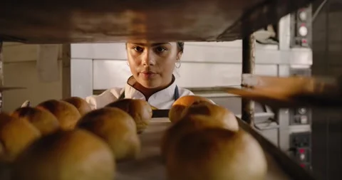 Noticing empty rack African American woman baker in chef coat placing rolls on Stock Footage 343368274