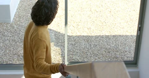 Noticing sunlit rooftop, Asian man climbing wooden staircase in loft, gripping Stock Footage 335454147