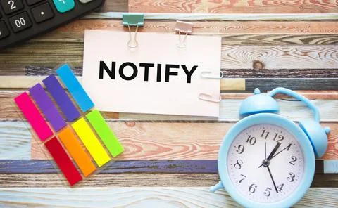Notify word written on a sticky note next to office supplies Stock Photos