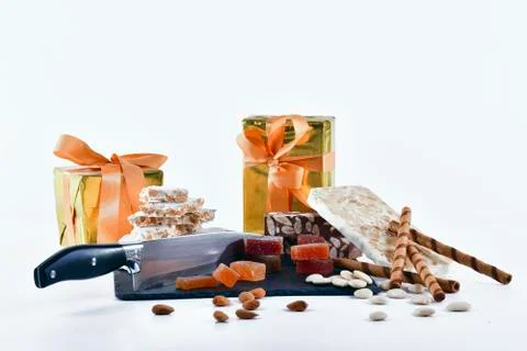 Nougat chunks, fruit paste, wafer sticks and a knife on a dark plate with wra Stock Photos