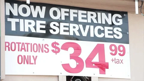 Now offering tire services rotations only 3499 35 dollars plus tax sign on wall Stock Footage 252043665
