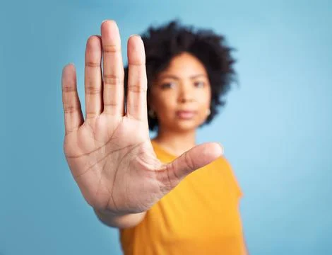 Now stop right here. a young woman standing alone against a blue background in Stock Photos