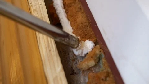 Nozzle of construction gun fills space under window frame by polyurethane foam 库存影片 77827101