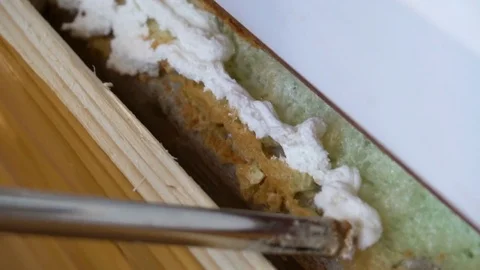 Nozzle of construction gun fills space under window frame by polyurethane foam Stock Footage