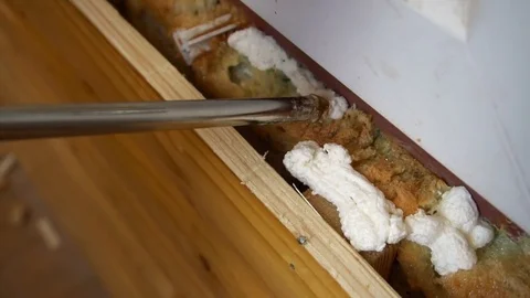 Nozzle of construction gun fills space under window frame by polyurethane foam Stock Footage 77828166