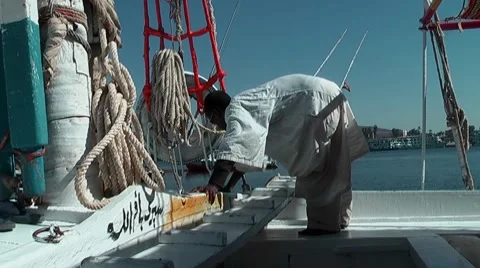 Nubian man cleans the deck of a nile felucca Видео 7734837