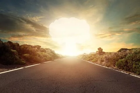Nuclear bomb explosion. Mushroom cloud on horizon and empty decert road Stock Photos