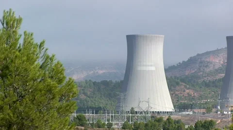 Nuclear cooling tower framed by pine tree in front Stock Footage 49963508