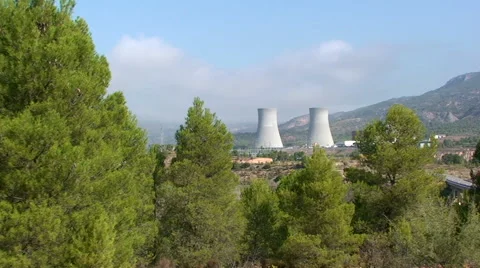 Nuclear cooling towers framed by pine trees Stock Footage 49963710