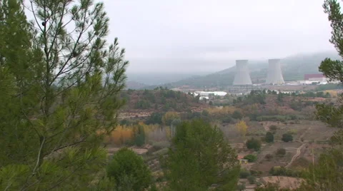 Nuclear hyperboloid cooling towers framed by trees, pan right Stock Footage 49928697