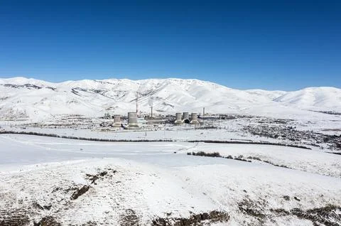 Nuclear powerplant on the field between snowy mountains on winter time Stock Photos