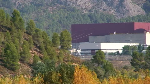 From nuclear reactor to cooling tower, tilt-pan over pine slope Stock Footage 49964704