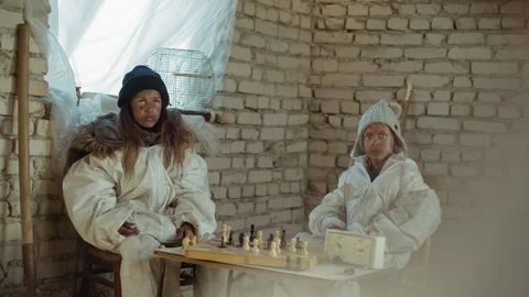 Nuclear war survivors in oversized jackets sitting silently inside abandoned 動画素材 329463924
