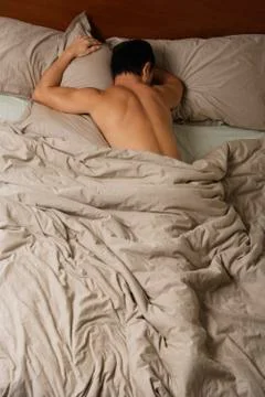 Nude man lying in bed. Stock Photos