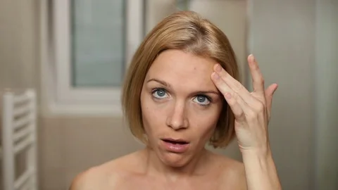 Nude woman frustrated while checking her skin in front of bathroom mirror. Stock Footage 79481950