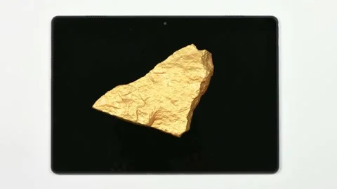 A nugget of gold moves across the surface of a tablet pc. Stock Footage 154814525
