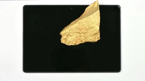 A nugget of gold moves across the surface of a tablet pc. Stock Footage 154814580