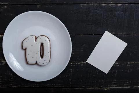 Number 10 shape gingerbread cookie on white plate standing on black table Stock Photos