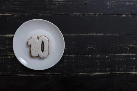 Number 10 shape gingerbread cookie on white plate standing on black table Stock Photos