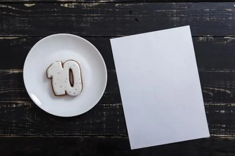 Number 10 shape gingerbread cookie on white plate standing on black table Stock Photos