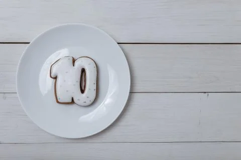 Number 10 shape gingerbread cookie on white plate standing on white table Stock Photos