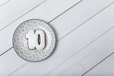 Number 10 shape gingerbread cookie on plate standing on white wooden table Stock Photos