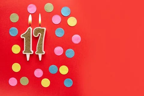 Number 17 on a red background with colored confetti. Happy birthday candles.. Stock Photos