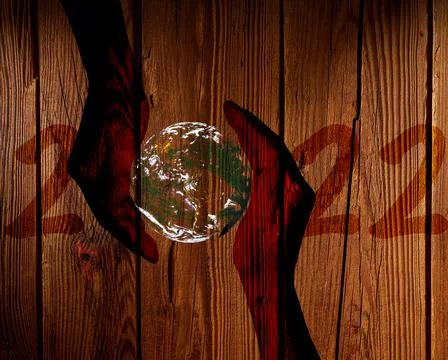 Number 2022 with the earth between two hands on a wood background 스톡 사진