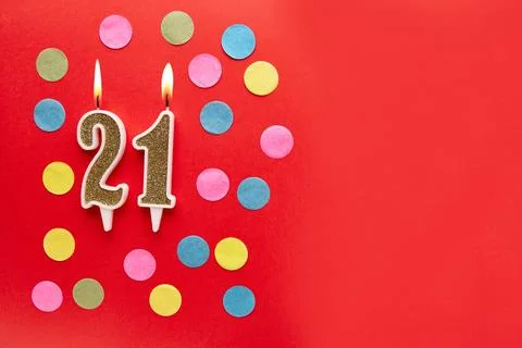 Number 21 on a red background with colored confetti. Happy birthday candles.. Stock Photos