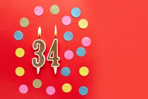 Number 34 on a red background with colored confetti. Happy birthday candles.. Stock Photos
