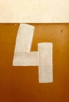 Number 4 painted with a roller on a warm orange wall 库存照片