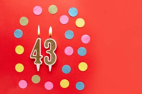 Number 43 on a red background with colored confetti. Happy birthday candles.. Stock Photos