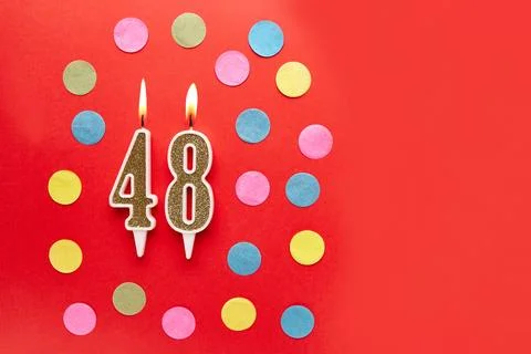 Number 48 on a red background with colored confetti. Happy birthday candles.. Stock Photos