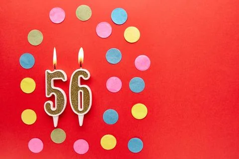 Number 56 on a red background with colored confetti. Happy birthday candles.. Stock Photos