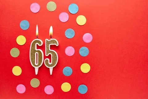 Number 65 on a red background with colored confetti. Happy birthday candles.. Stock Photos