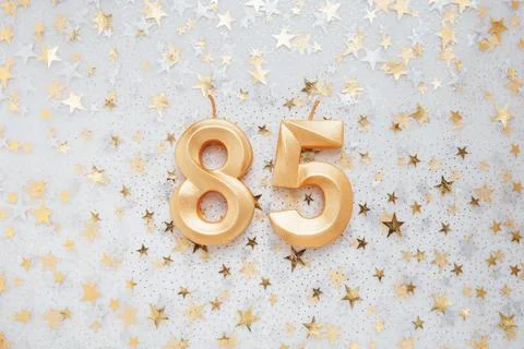 Number 85 eighty five golden celebration birthday candle on Festive Background. Stock Photos