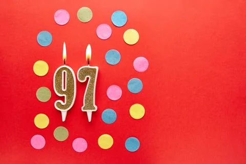 Number 97 on a red background with colored confetti. Happy birthday candles.. Stock Photos