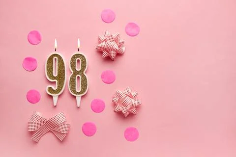 Number 98 on pastel pink background with festive decor. Happy birthday cand.. Stock Photos
