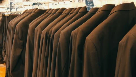 Number of identical-colored men's suits hanging on a hanger in a clothing store Video stock 101211148
