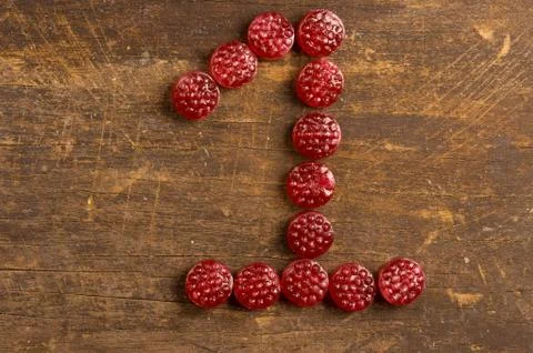 The number one shaped by raspberry hard candy on wooden surface Stock Photos